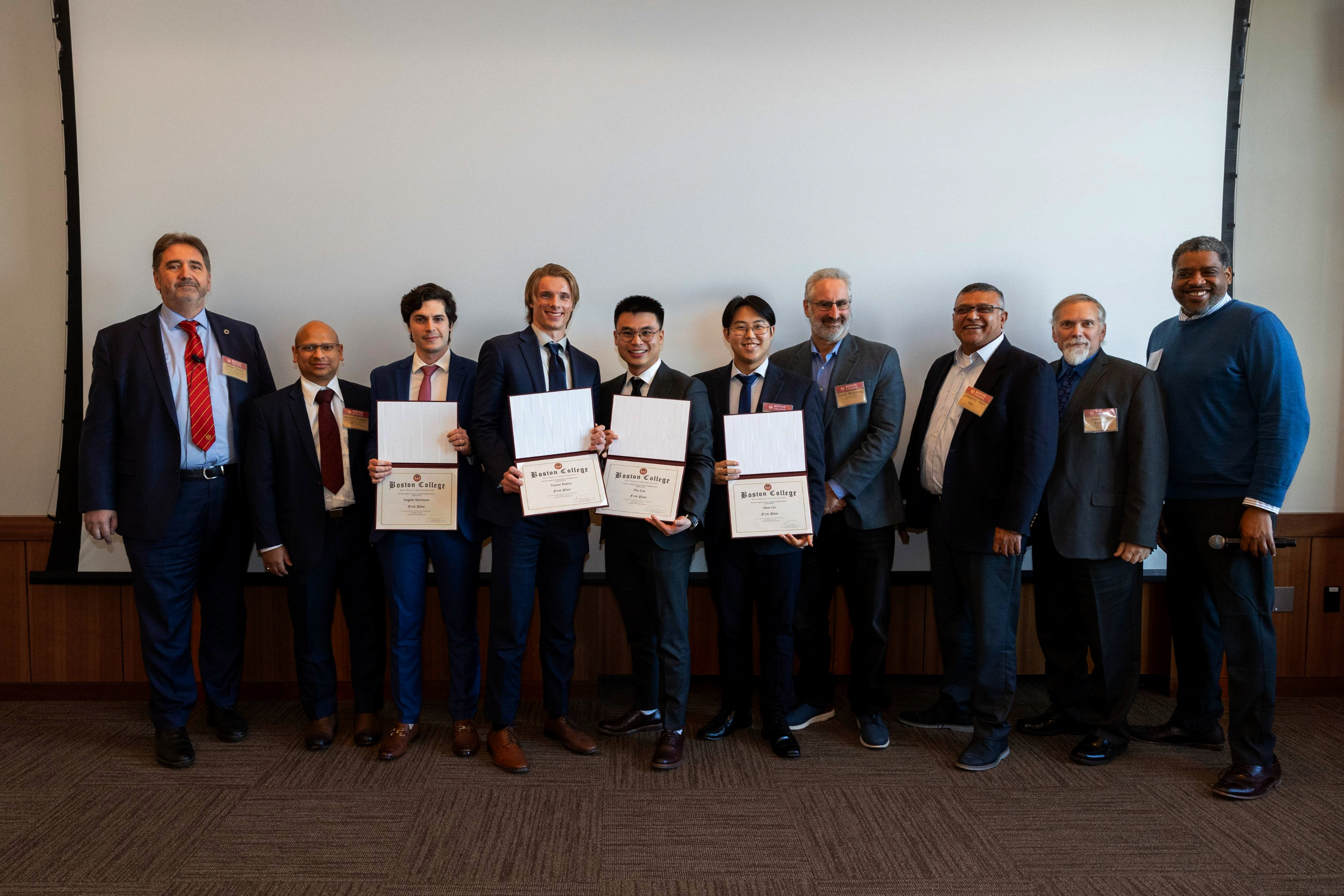 A group of individuals poses for a photo, with several holding certificates after being awarded $3000 in prizes from Myridius’ representatives.