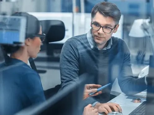 Female-Project-Supervisor-Talks-to-a-Male-Industrial-Engineer-who-Works-on-Personal-Computer